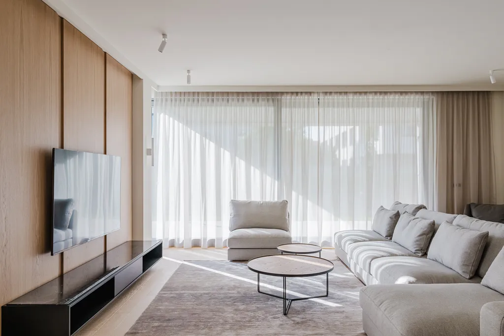 Living room with sheer curtains and patches of sun on the rug