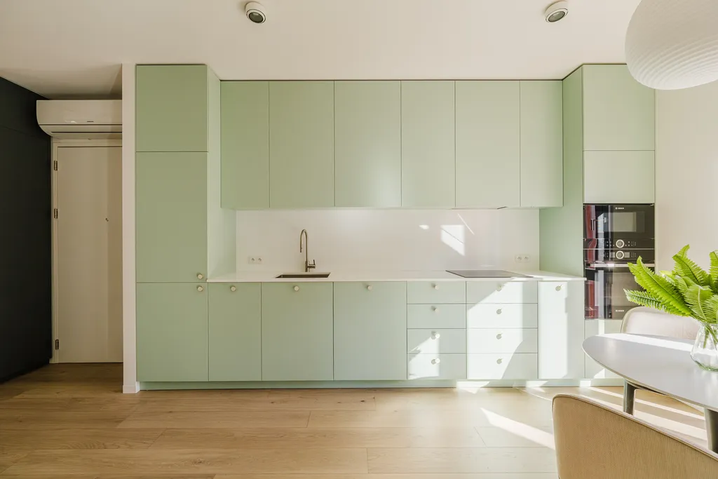 Frame from an apartment with a green sofa and a mint kitchen